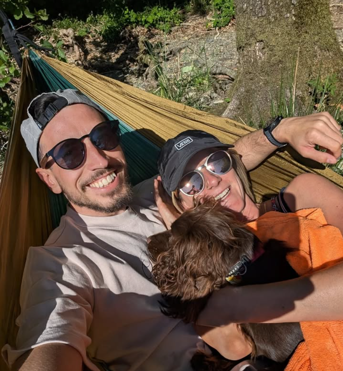 Man and women and dog in a hammock smilling