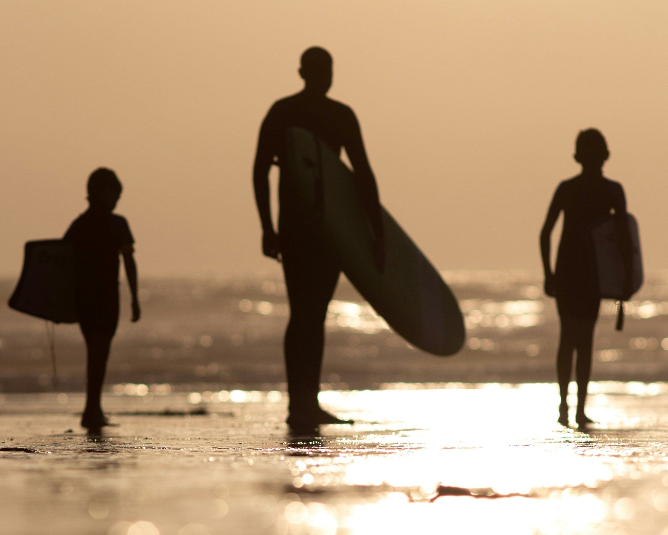 parent and two children walking out to surf at Polzeath beach
