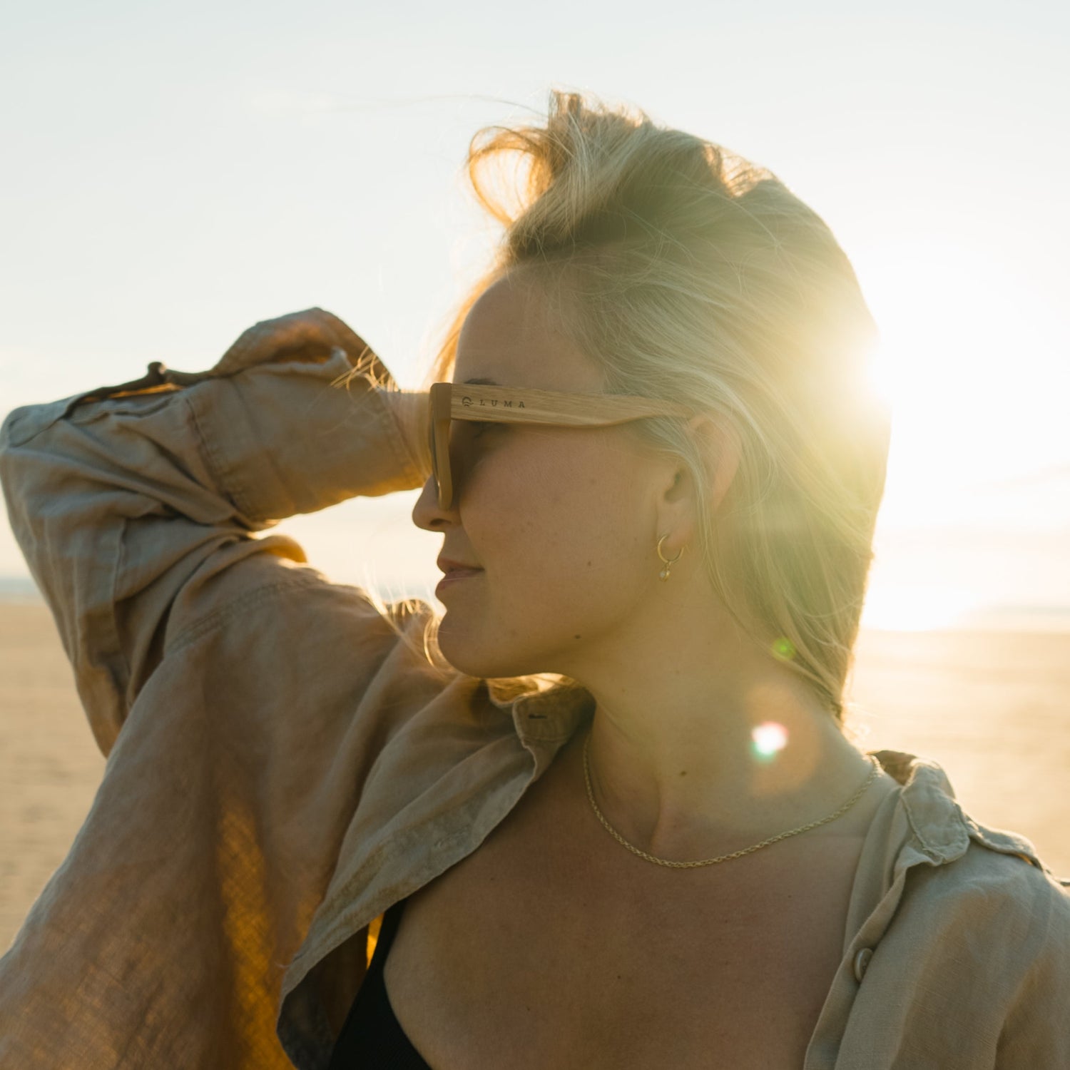Side view of woman wearing Luma Polzeath sunglasses with sun behind her