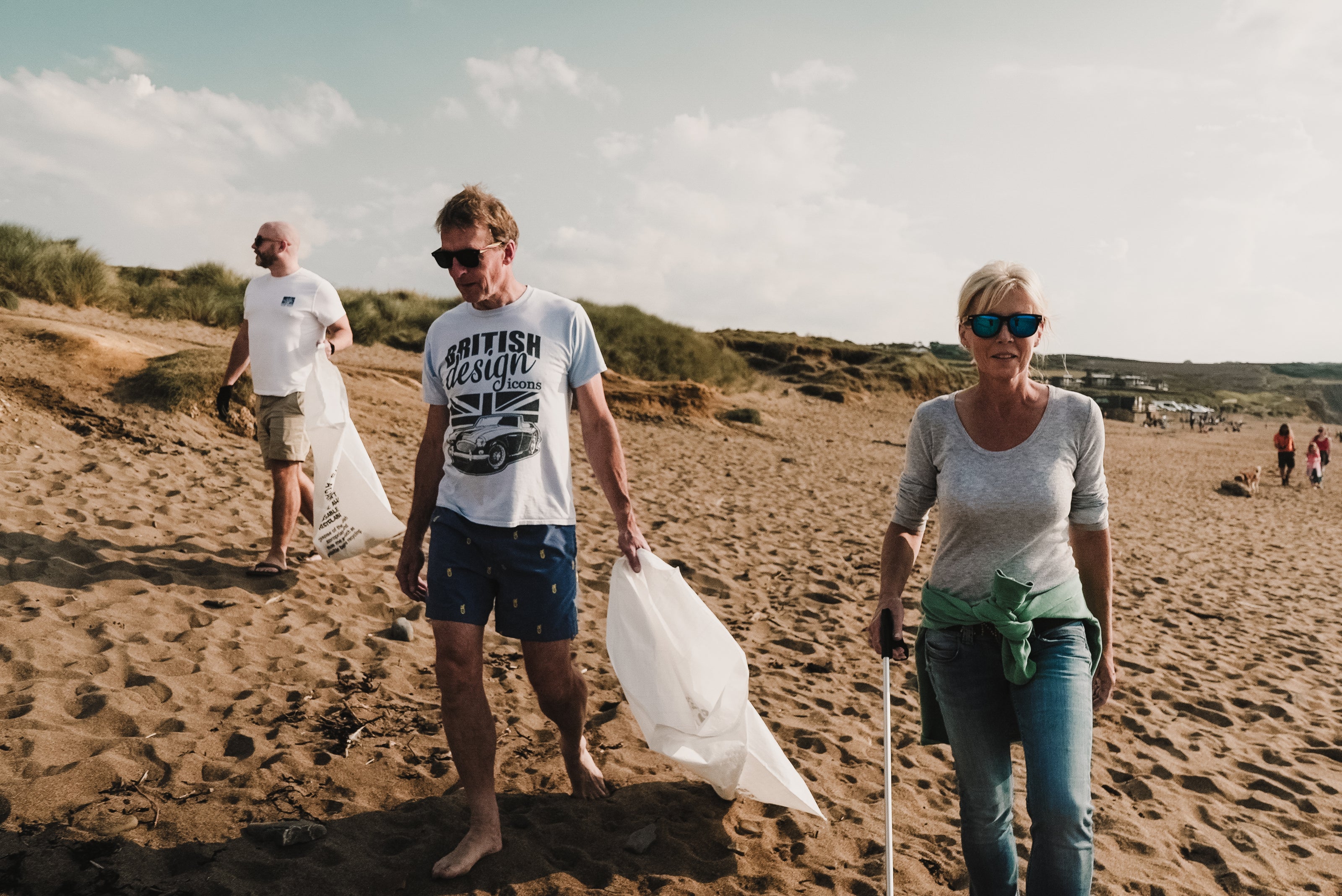 Three adults walking on beach participating in Cornwall beach clean